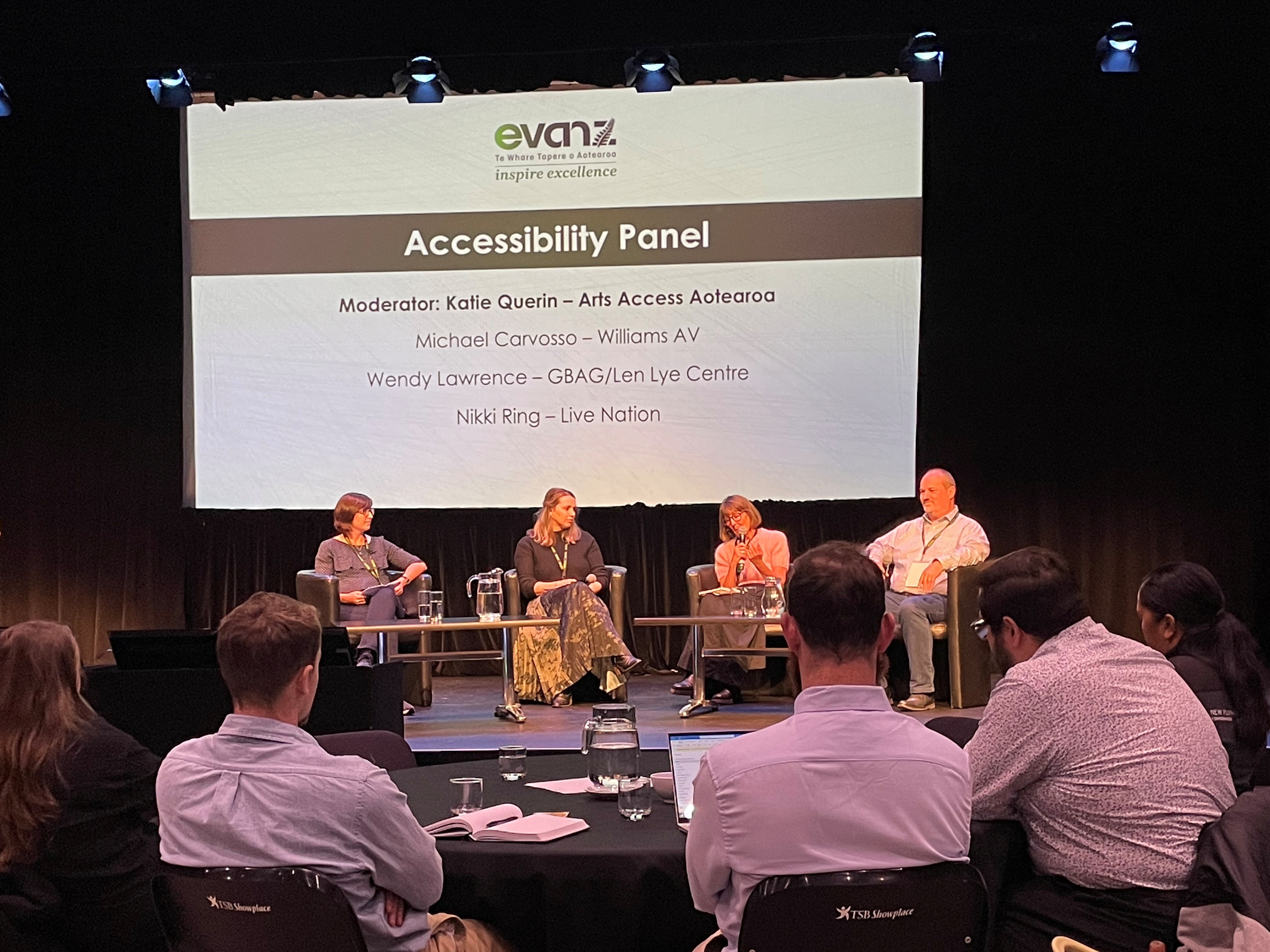 From left to right, Katie Querin, Nikki Ring, Wendy Lawrence and Michael Carvosso sit on stage addressing EVANS during an accessibility panel discussion.